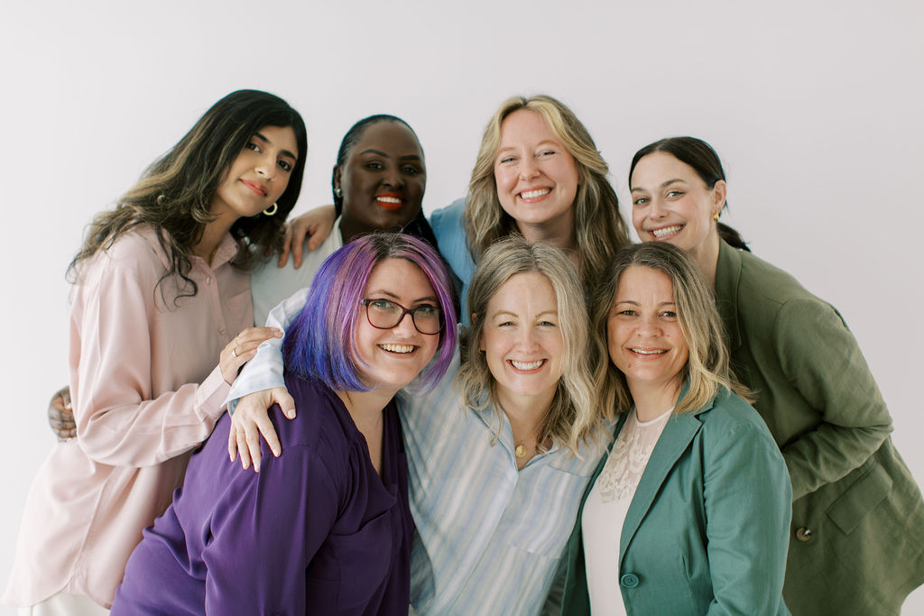 Seven psychotherapists pose together, smiling at the camera against a plain white background.