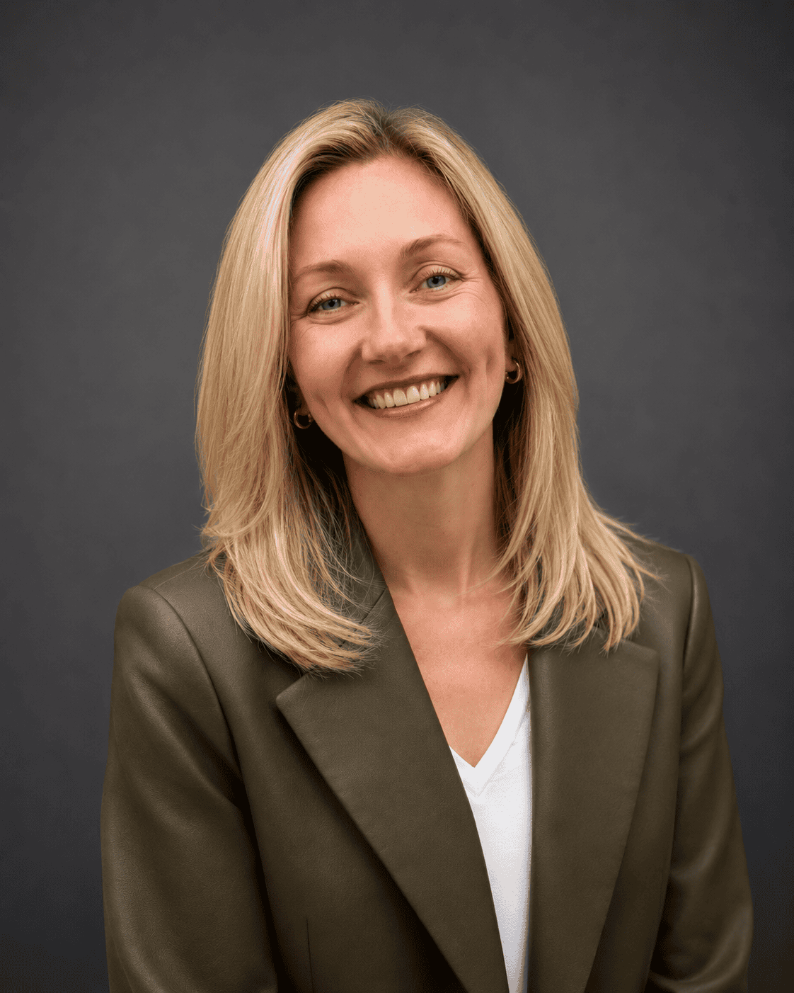 Smiling registered psychotherapist with blonde hair in a dark blazer and white top, posed as if ready to meet you where you are at.
